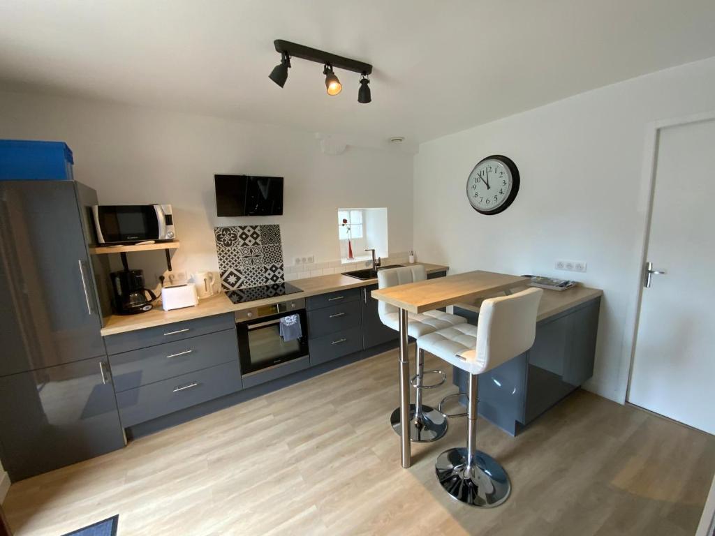 uma cozinha com uma mesa e um relógio na parede em La MAIS'ANGE - Charmante maison proche centre em Blois