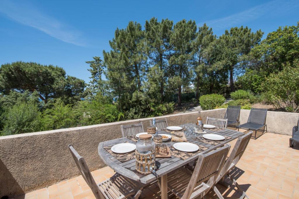 une table et des chaises en bois sur une terrasse dans l'établissement La Pinède - Maison proche plages, à Pietrosella