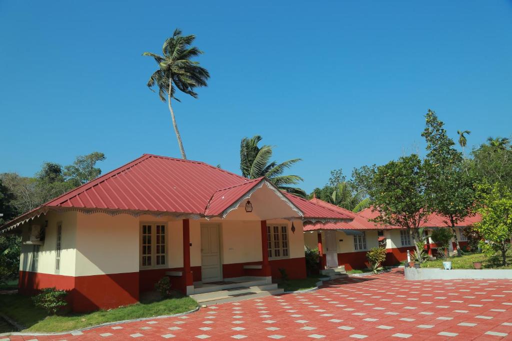 a house with a red roof and a palm tree at Kandamath Heritage Resort in Kolattupuzha