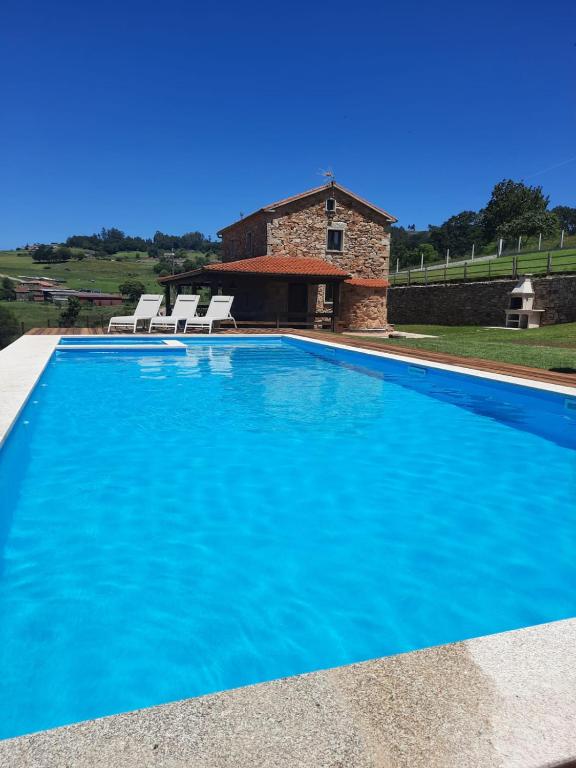 a large blue swimming pool with a stone house at Miña Nai, Casa Rural in Lalín
