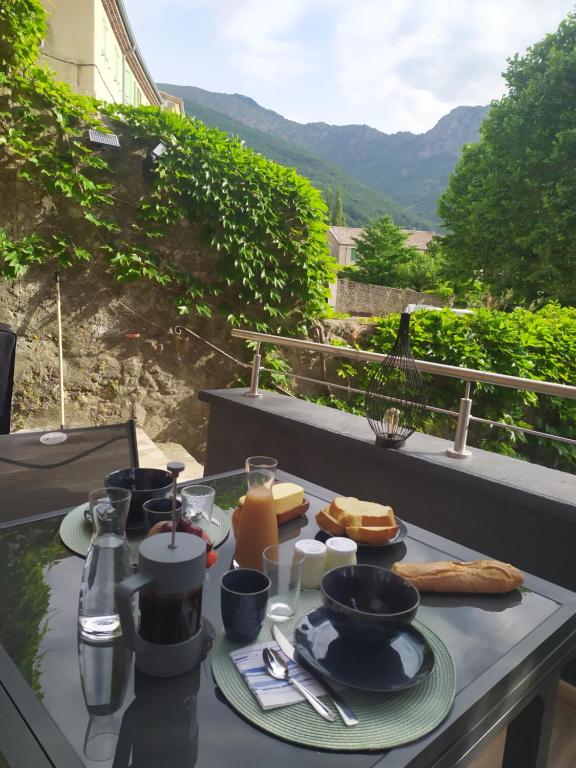 einen Frühstückstisch mit Essen auf einem Balkon mit Aussicht in der Unterkunft Au Pied de la Béalière in Montpezat-sous-Bauzon