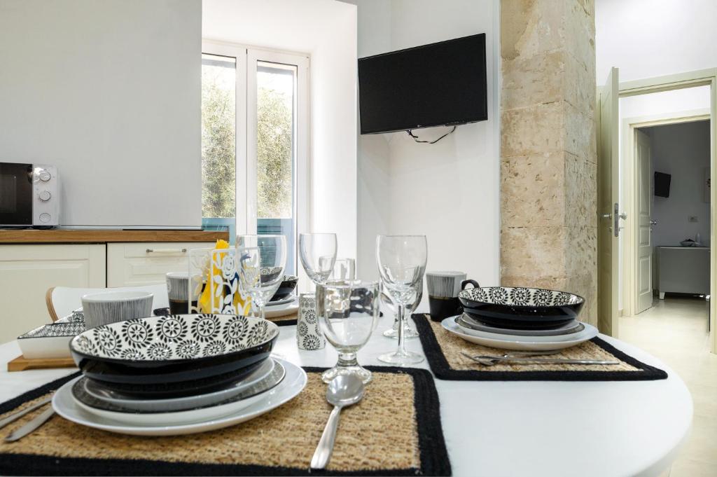 un tavolo con piatti e bicchieri da vino sopra di ELORO - Guest Houses a Noto