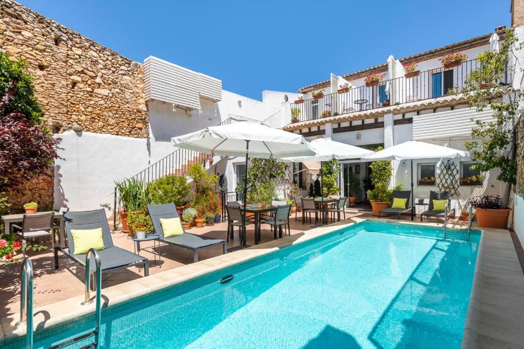 a swimming pool with chairs and umbrellas next to a building at Casa Sibarita in Rafelguaraf