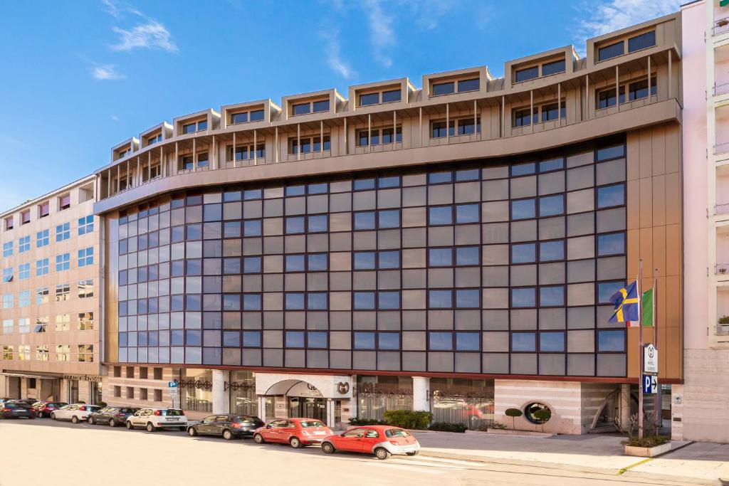 un grand bâtiment avec des voitures garées devant lui dans l'établissement Hotel Giberti & Spa, à Vérone