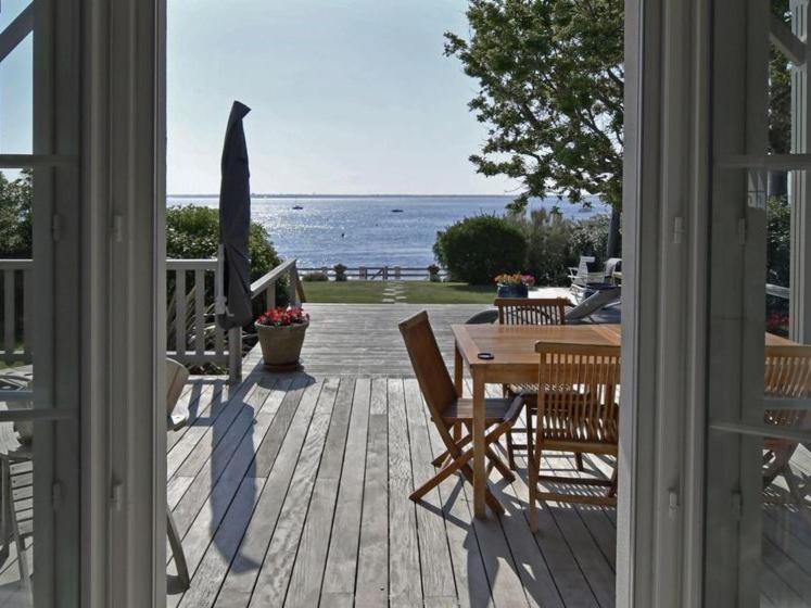 une terrasse couverte avec une table et des chaises et une vue sur l'océan. dans l'établissement Villa De La Plage, à Pyla-sur-Mer