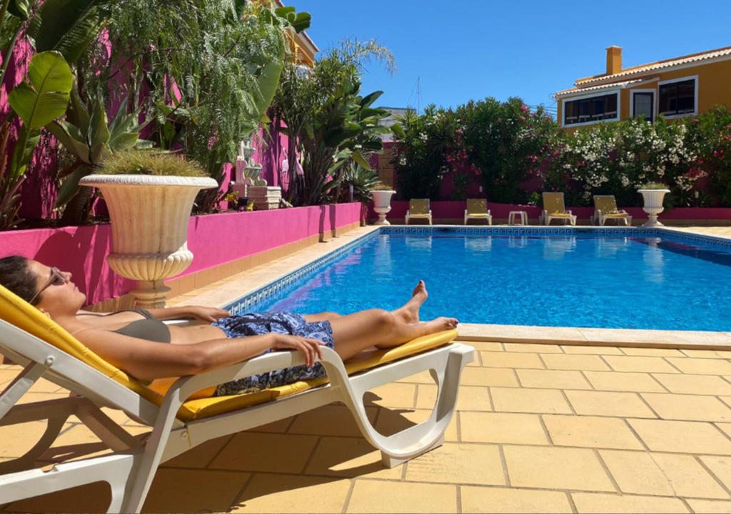 a man laying on a chair next to a swimming pool at Casa Concha - Peaceful and Relaxing in Lagos