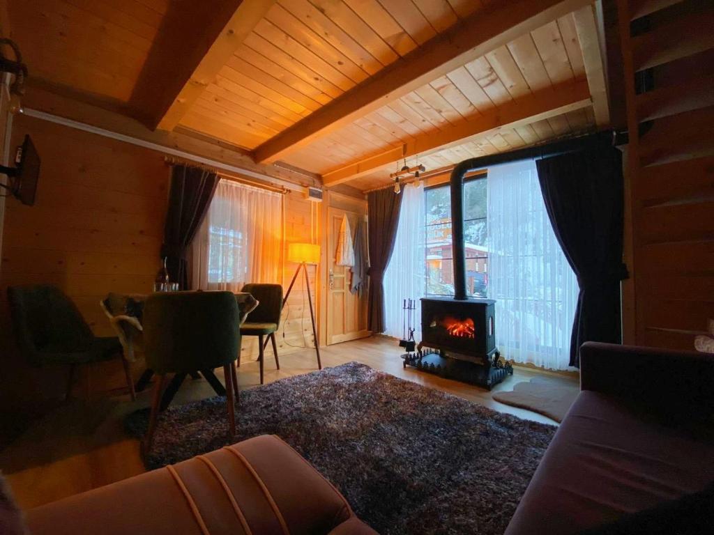 a living room with a fireplace and a table and chairs at Ayder Bulut Dağevi Bungalow in Ayder Yaylasi