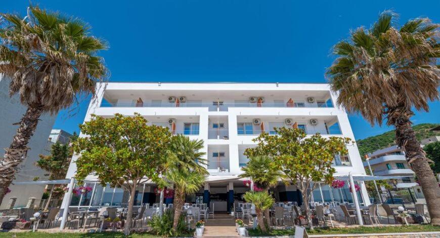 een groot wit gebouw met palmbomen ervoor bij Hotel Besani in Durrës