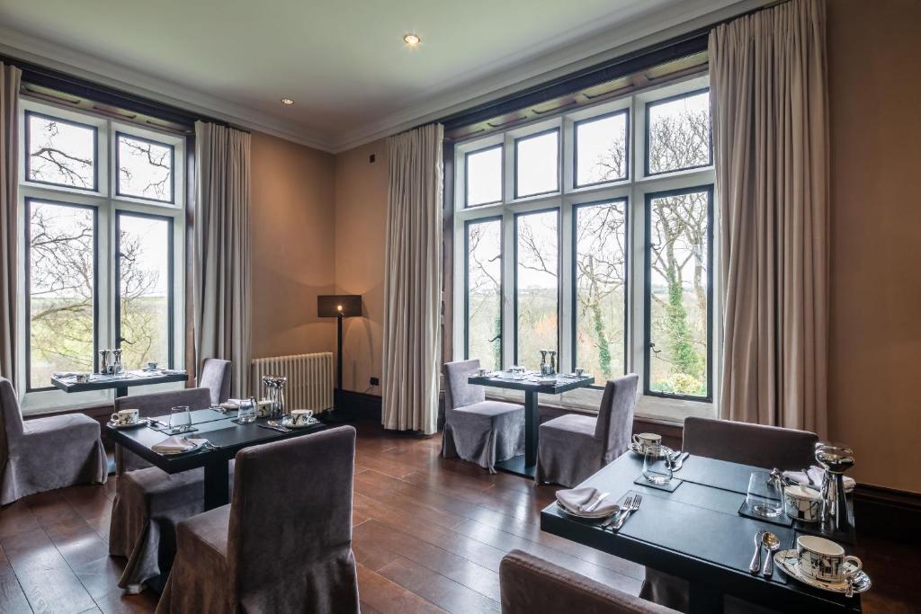 a restaurant with tables and chairs and large windows at Penrhiw Priory in St. Davids