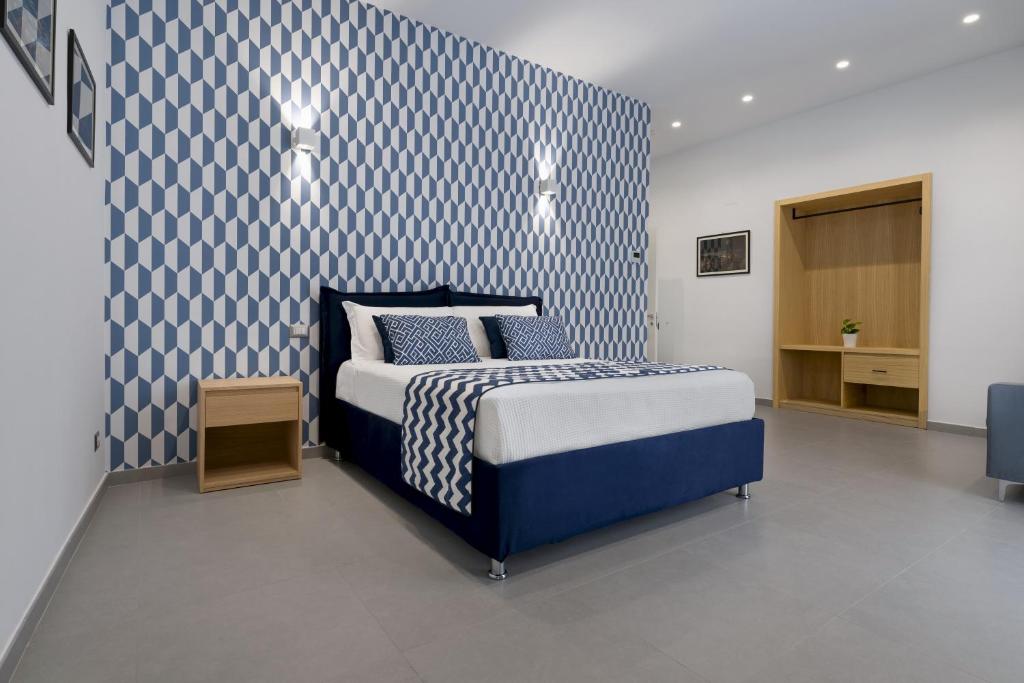 um quarto com uma cama com uma parede estampada em azul e branco em HSuites Luxury B&B em Castellammare di Stabia