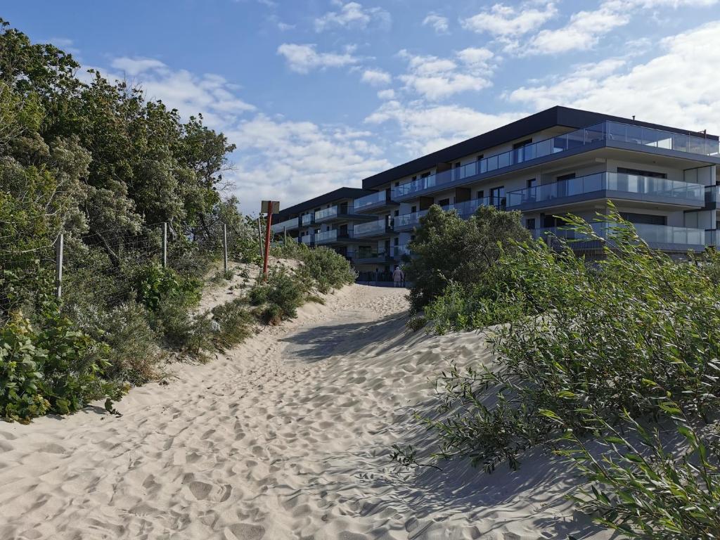 a building on the beach next to a sand road at Apartament LUCKY 7 Gardenia Seaside in Dziwnów