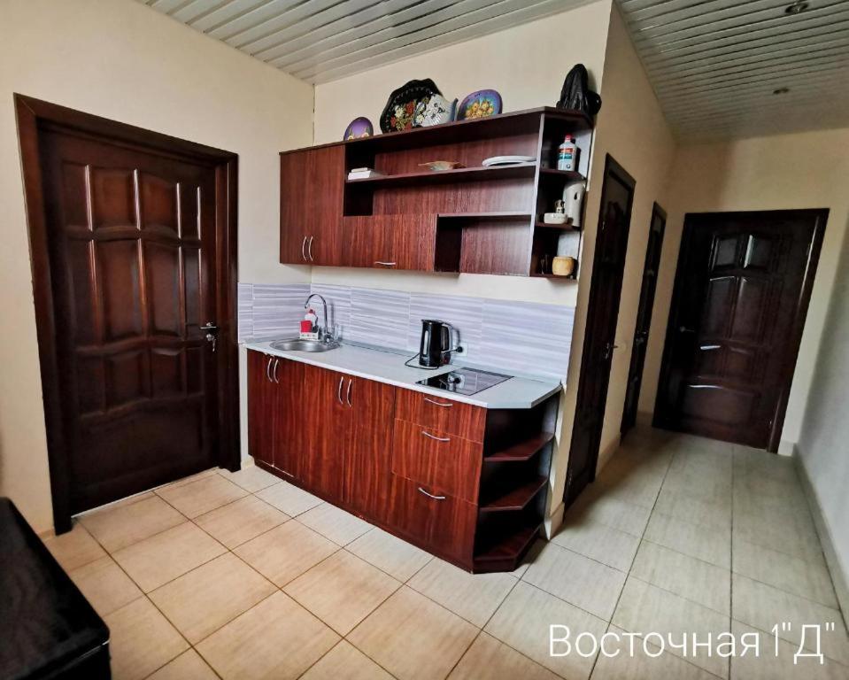 ジヴェエヴォにあるGuest House on Vostochnaya d 1Dのキッチン(シンク、木製キャビネット、ドア付)