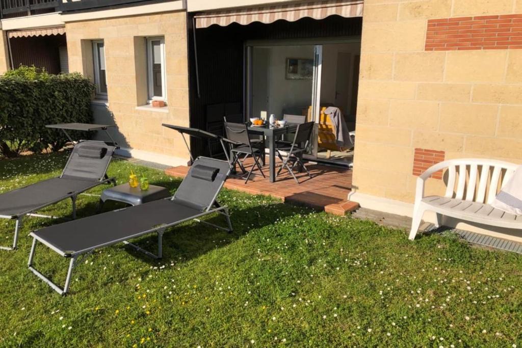 un patio con sillas, una mesa y una mesa con sillas en Beautiful Apartment With Garden, en Cabourg