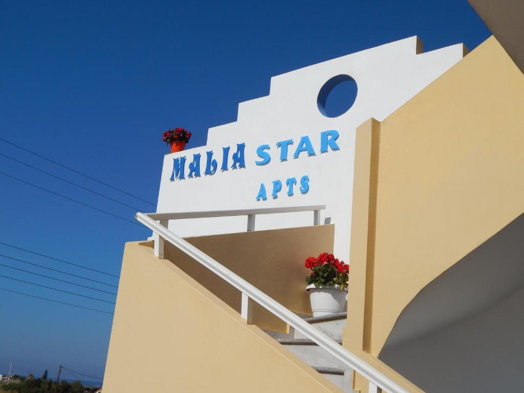 Malia Star Apartments في ماليا: علامة على جانب مبنى به زهور