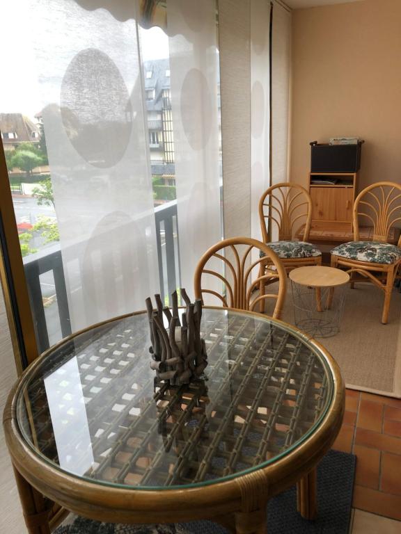 una mesa de cristal y sillas en una habitación con ventana en Soleil Levant, en Villers-sur-Mer