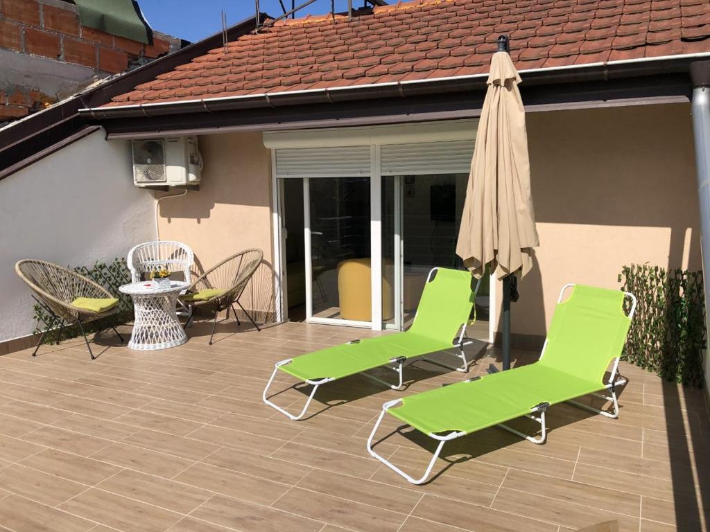 une terrasse avec des chaises vertes, un parasol et une table dans l'établissement Apartment N & N, à Struga