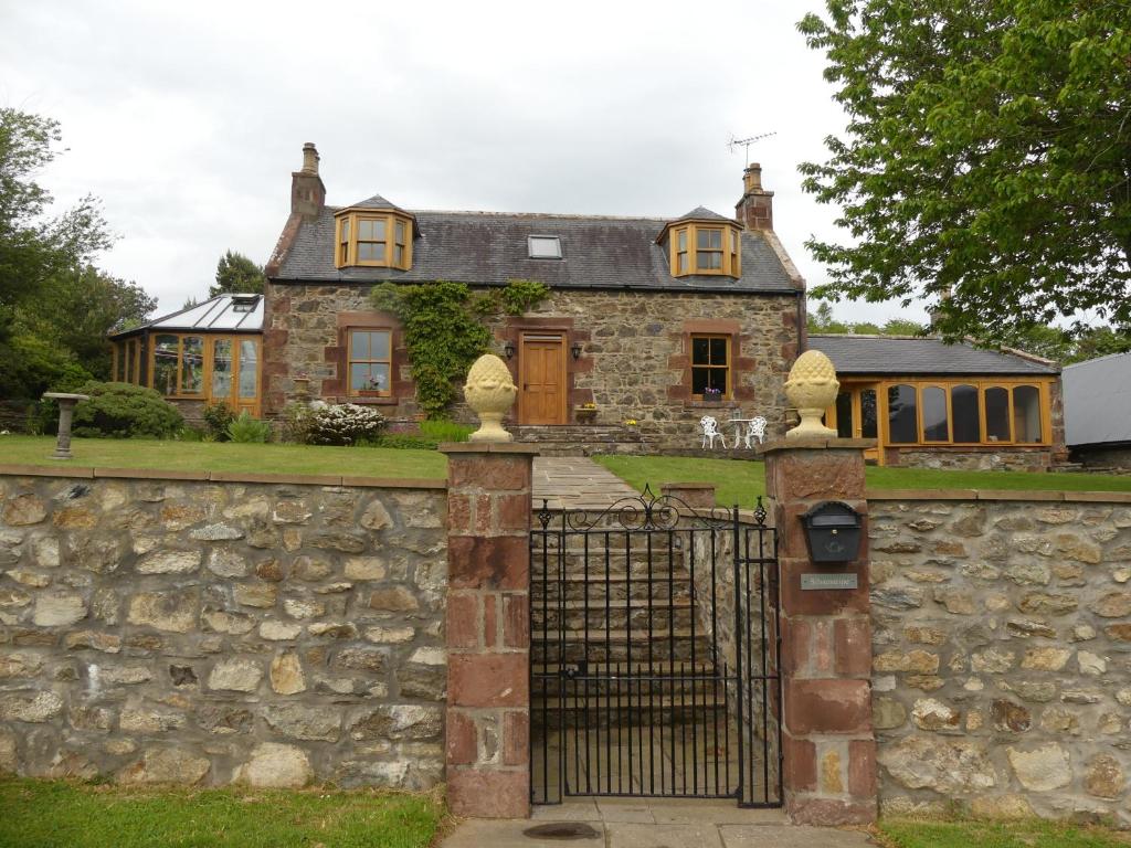 an old stone house with a gate and a stone wall at Silverstripe in Turriff