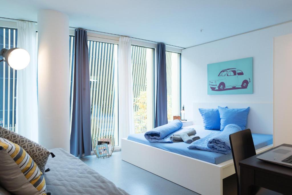 - une chambre avec un lit doté de draps bleus et une fenêtre dans l'établissement HITrental Allmend Standard Studios, à Lucerne