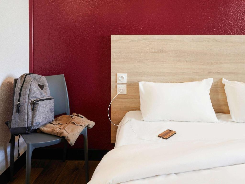 1 dormitorio con 1 cama y 1 mochila en una silla en HotelF1 Perpignan Sud en Perpiñán