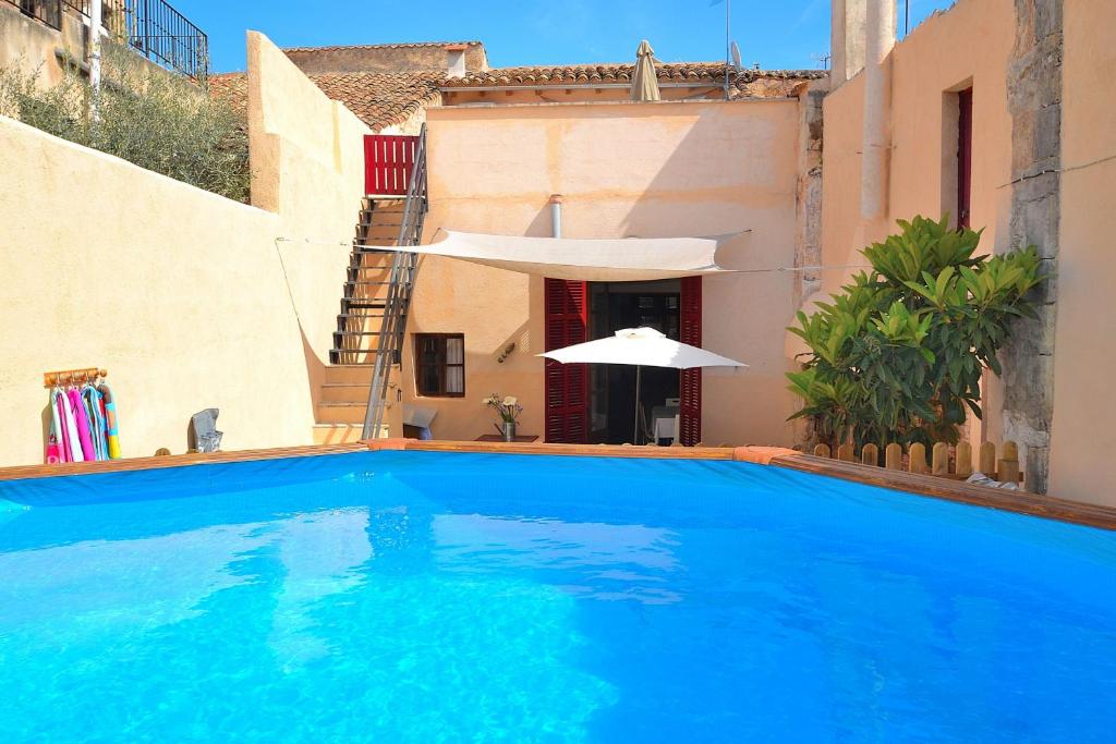 a large blue swimming pool next to a building with an umbrella at Casa Es Forn 229 by Mallorca Charme in Petra