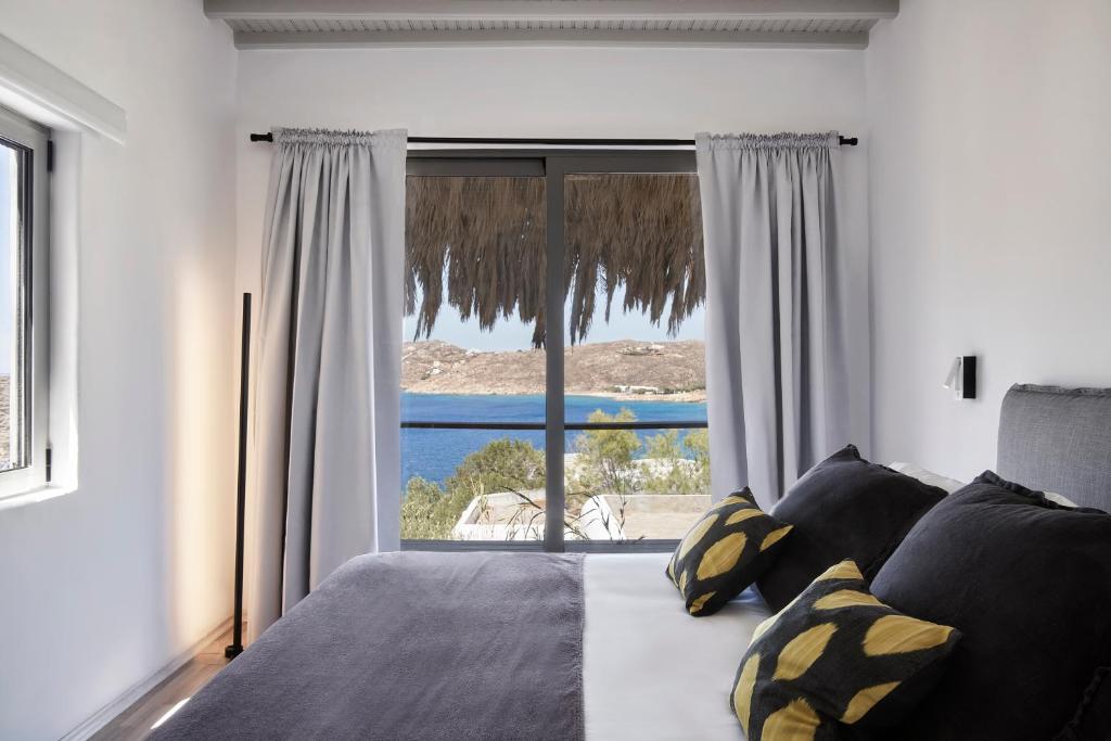 Schlafzimmer mit einem großen Fenster mit Meerblick in der Unterkunft Boheme Beach Houses in Elia
