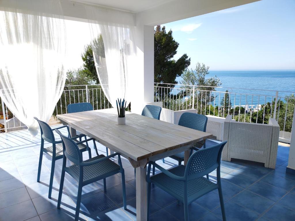 una mesa de madera y sillas en un balcón con vistas al océano en Ville Agnuli Case Vacanza, en Mattinata