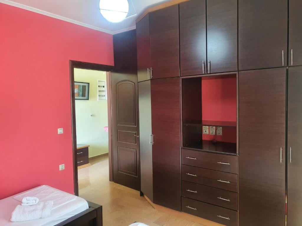 a room with wooden cabinets and a red wall at Mihal Suites in Sarandë