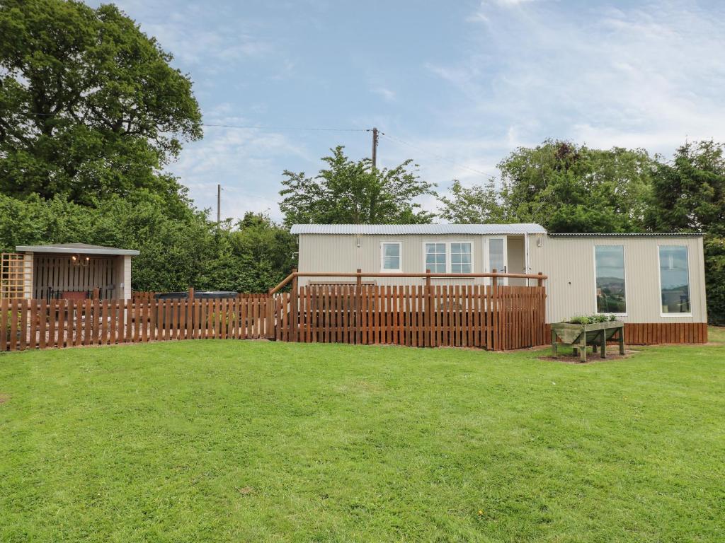 a house with a fence and a picnic table in a yard at Shepherds Hut in Rugeley