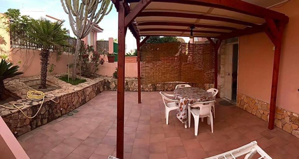 un patio con mesa y sillas bajo una pérgola en Lopadusa trilo 1 en Lampedusa