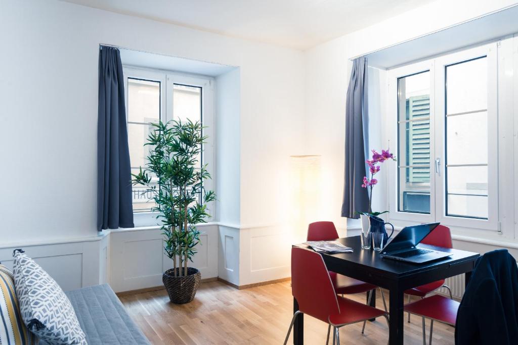 a dining room with a table and chairs and windows at HITrental Old Town Apartments in Lucerne