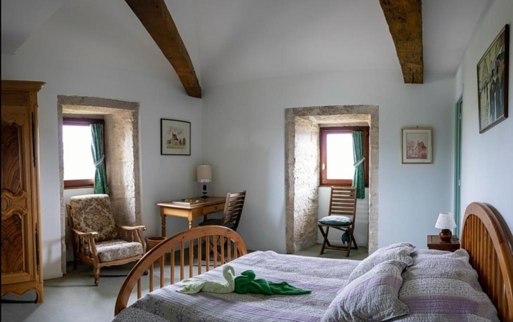 a bedroom with a bed and a table and chairs at La Maison Royale in Pesmes