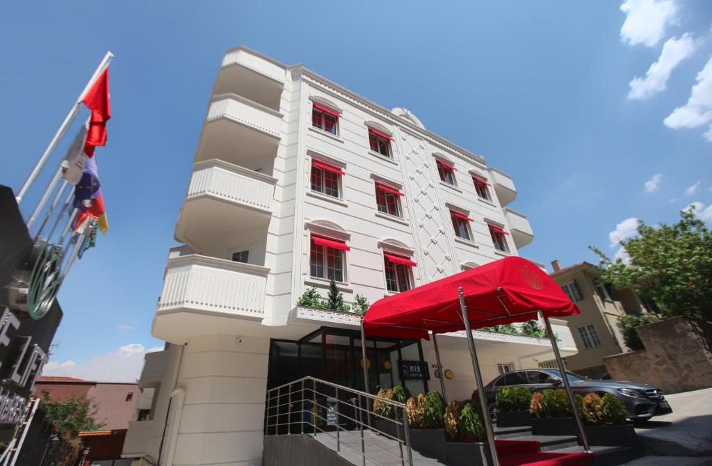 een wit gebouw met rode ramen en een rode paraplu bij The Life Hotel & Spa in Yenimahalle