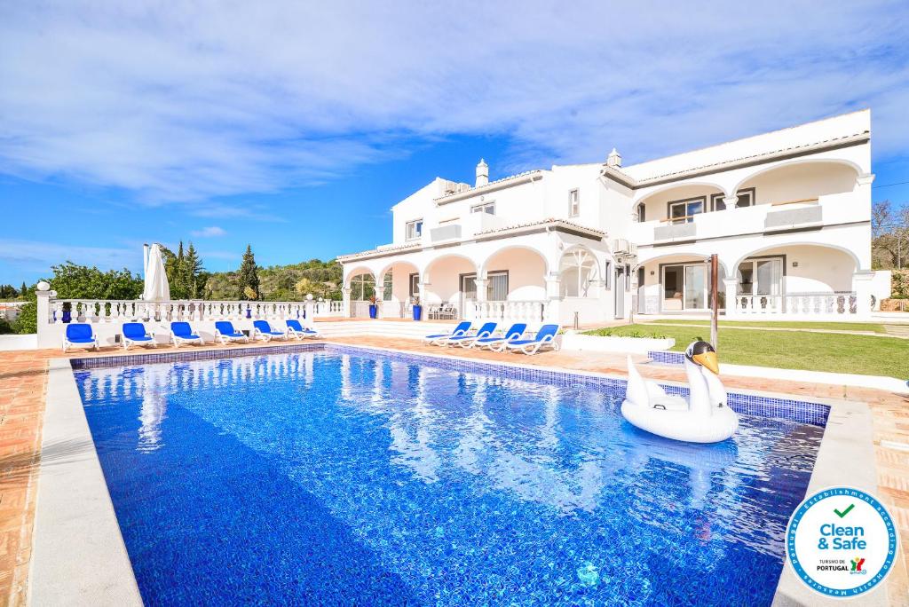 a large white house with a swimming pool with blue chairs at Vila Vale Mouro by OCvillas in Faro