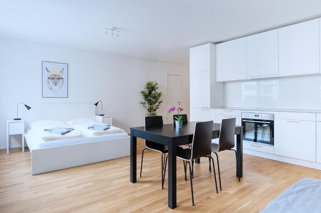 a kitchen and dining room with a black table and chairs at HITrental Messe Apartments in Basel