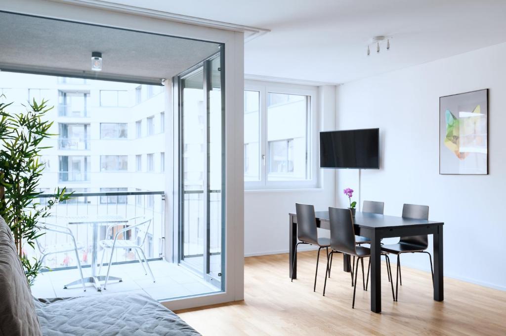 ein Wohnzimmer mit einem Tisch und Stühlen sowie ein Esszimmer in der Unterkunft HITrental Basel Apartments in Basel