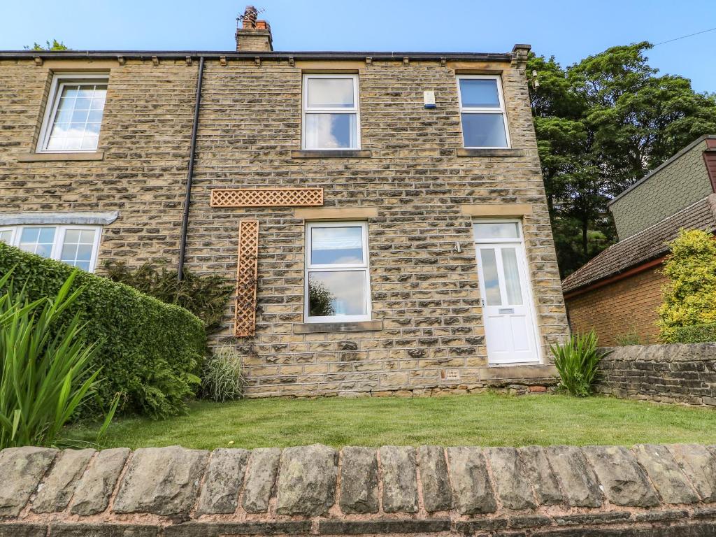 a brick house with white doors and windows at Sunnyside Villa in Holmfirth