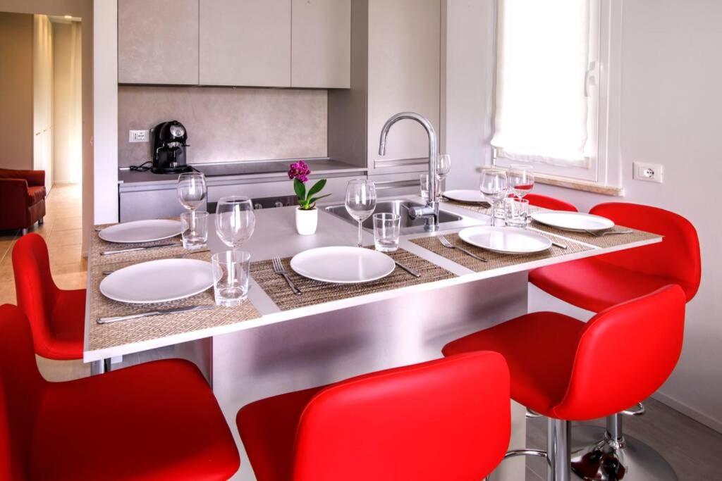 eine Küche mit einem Tisch mit roten Stühlen und einem Waschbecken in der Unterkunft Casa Plauto con appartamento grande in Bellaria-Igea Marina