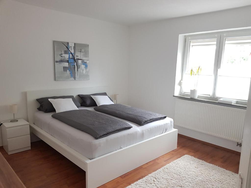 Dormitorio blanco con cama blanca y ventanas en Ferienwohnung im Springerhof, en Lohr