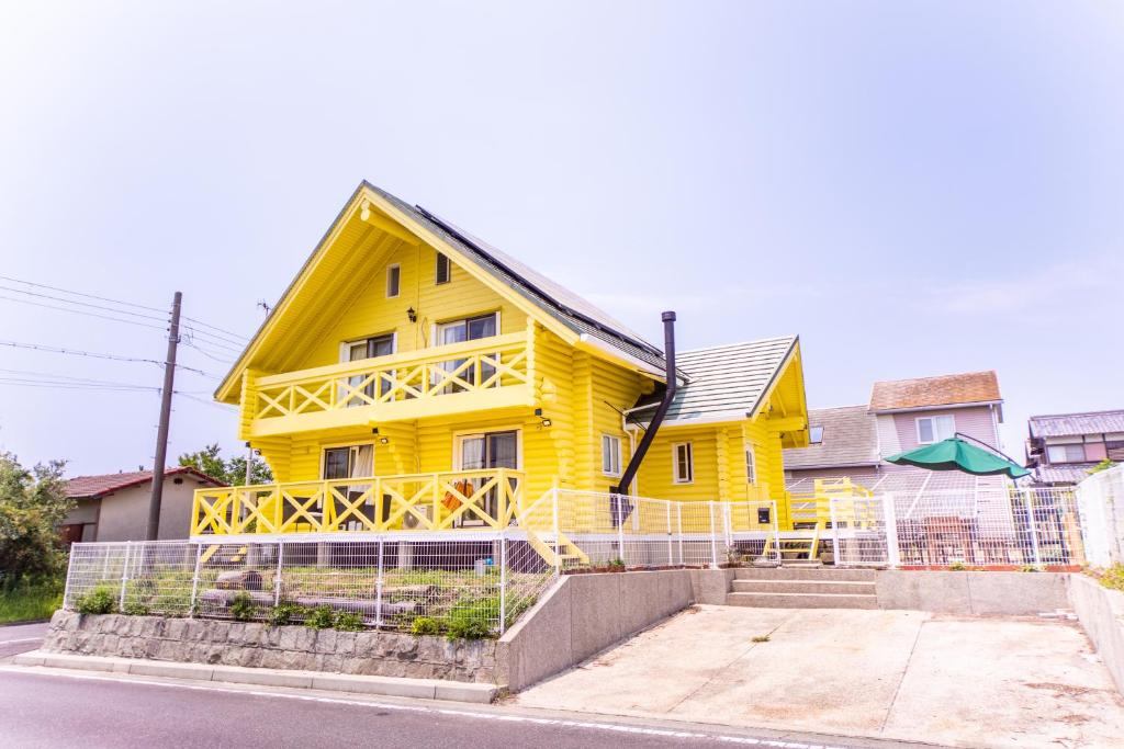 uma casa amarela ao lado de uma rua em Awaji Large Log house in Goshiki em Sumoto