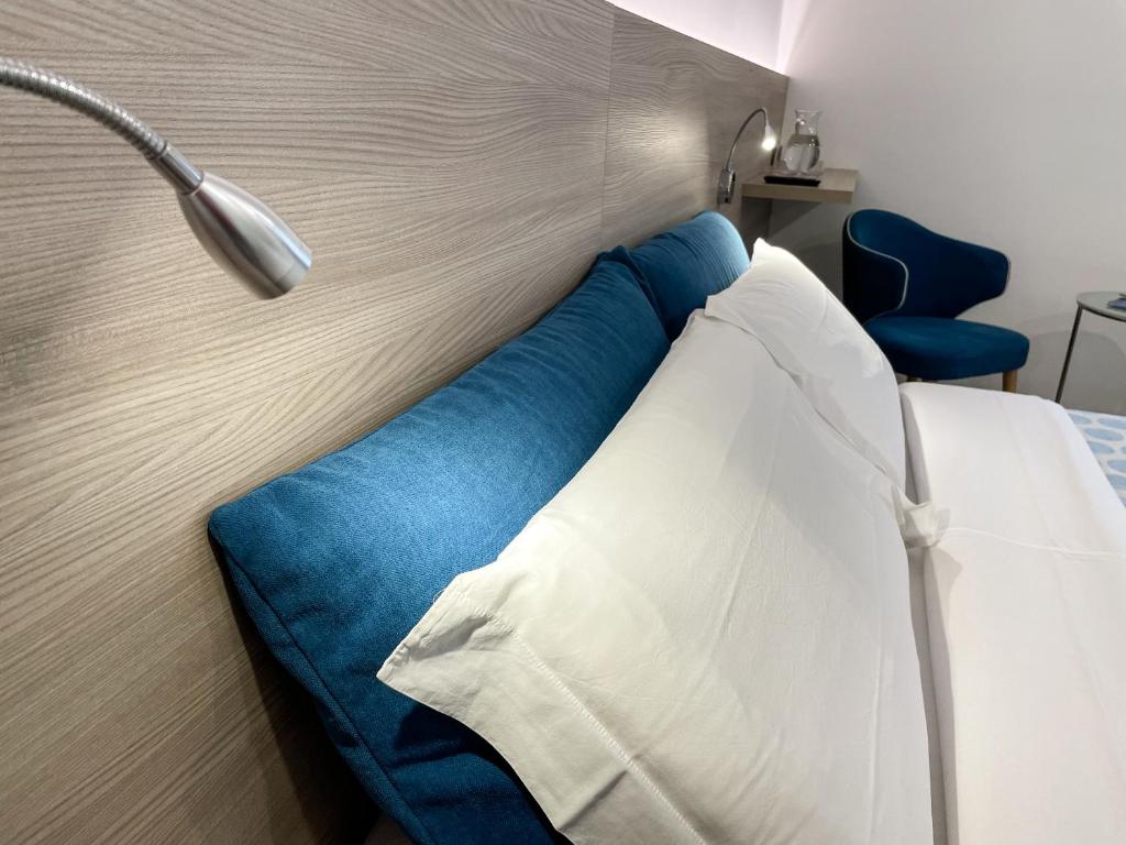 ein Bett mit einem blauen und weißen Kissen und einer Lampe in der Unterkunft Hotel Locanda Alla Perla in Ledro