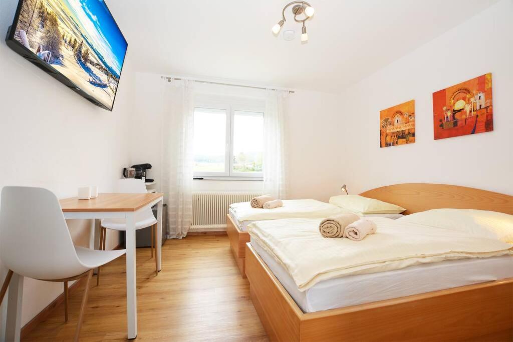 2 Betten in einem Zimmer mit einem Schreibtisch und einem Tisch in der Unterkunft Alpenblick - Modernes Apartment in Ruhelage in Villach