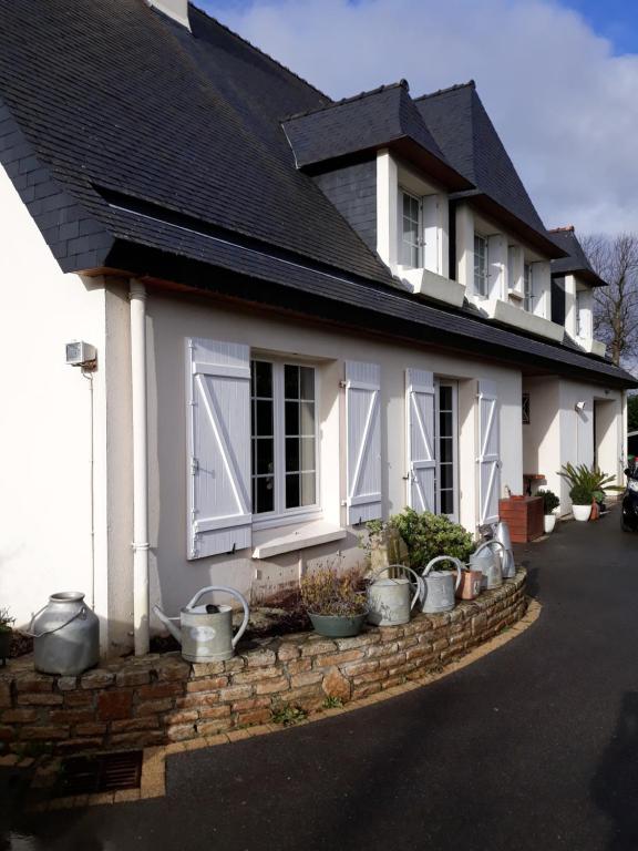 una casa bianca con piante in vaso davanti di Chambre sympa belle propriété a Gouesnou