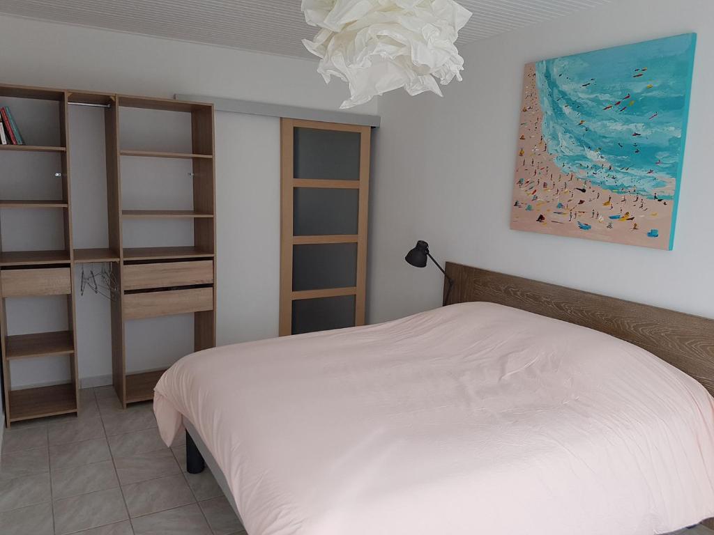 ein Schlafzimmer mit einem weißen Bett und einem Kronleuchter in der Unterkunft 500m de la plage des Boucholeurs - Maison pour 5 in Barbâtre