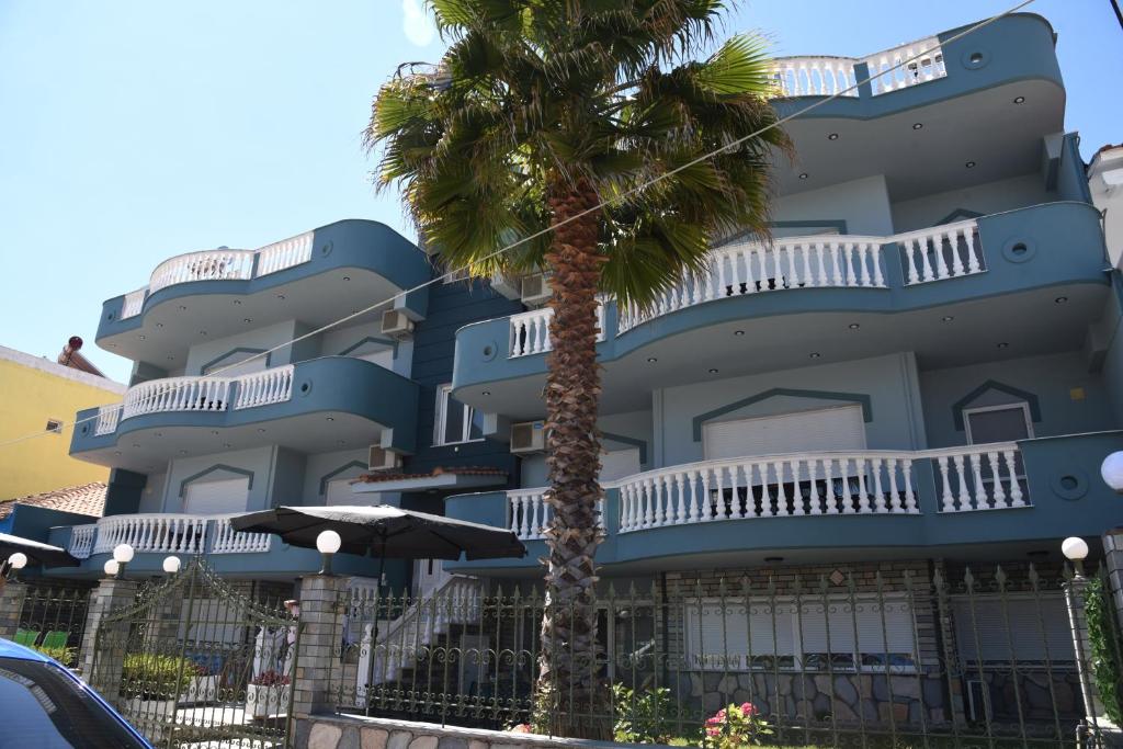 a blue building with a palm tree in front of it at Complex Summer Memories in Keramoti