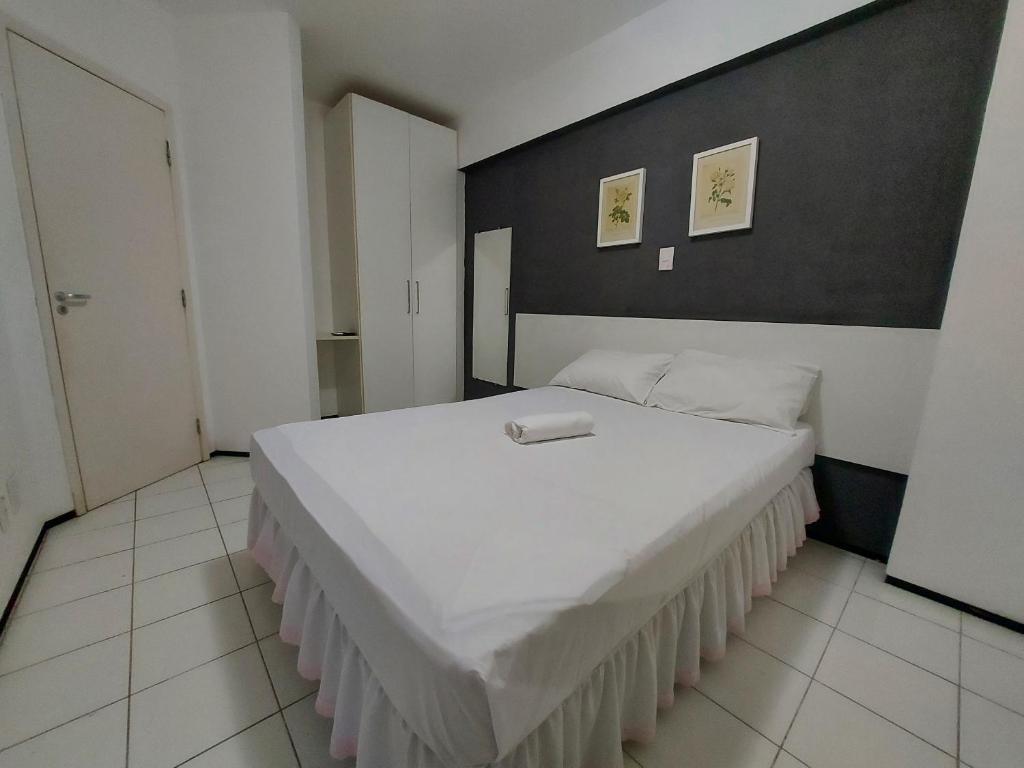 1 dormitorio con 1 cama blanca grande y pared negra en Flat Biarritz - Ao lado da Litoranea - Ferreira Hospedagens, en São Luís