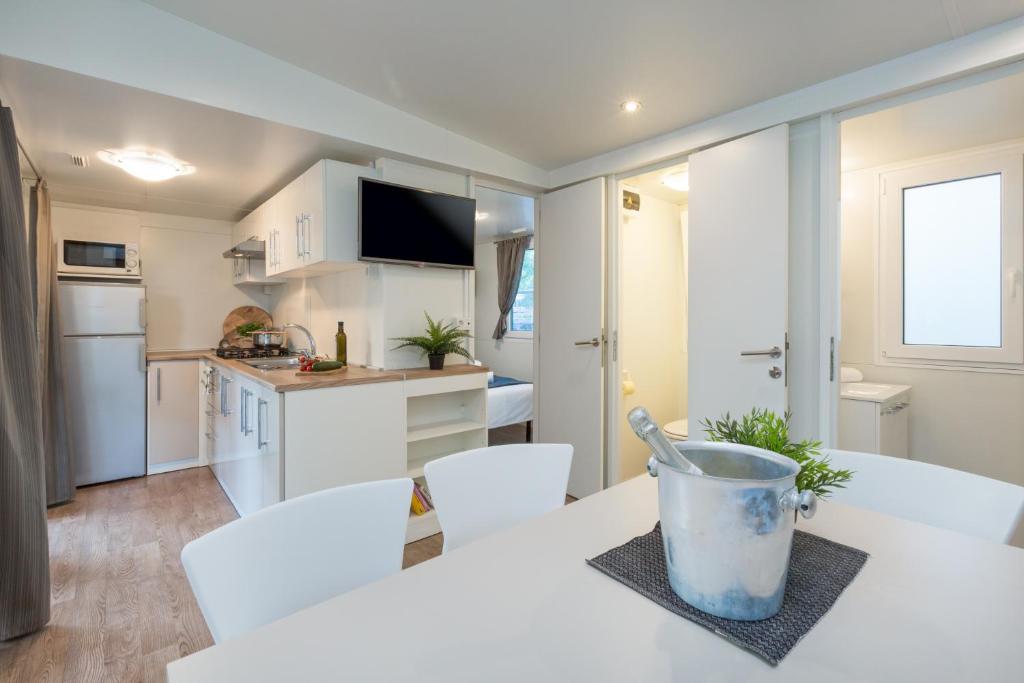 a kitchen with white cabinets and a white table and chairs at Mobile Homes Banko in Bijela Uvala and Zelena laguna in Poreč