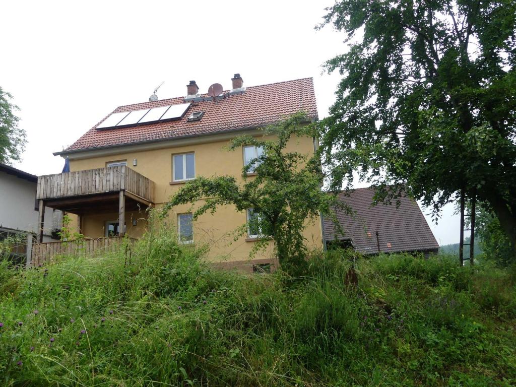 una casa amarilla con paneles solares encima en Fewo Im gruenen Eck 1, en Airlenbach