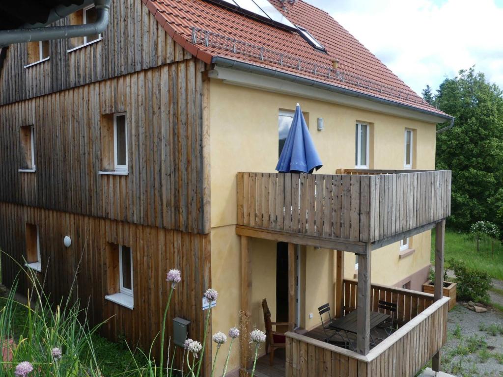 a house with a deck and a blue umbrella on it at Fewo Im gruenen Eck 2 in Airlenbach