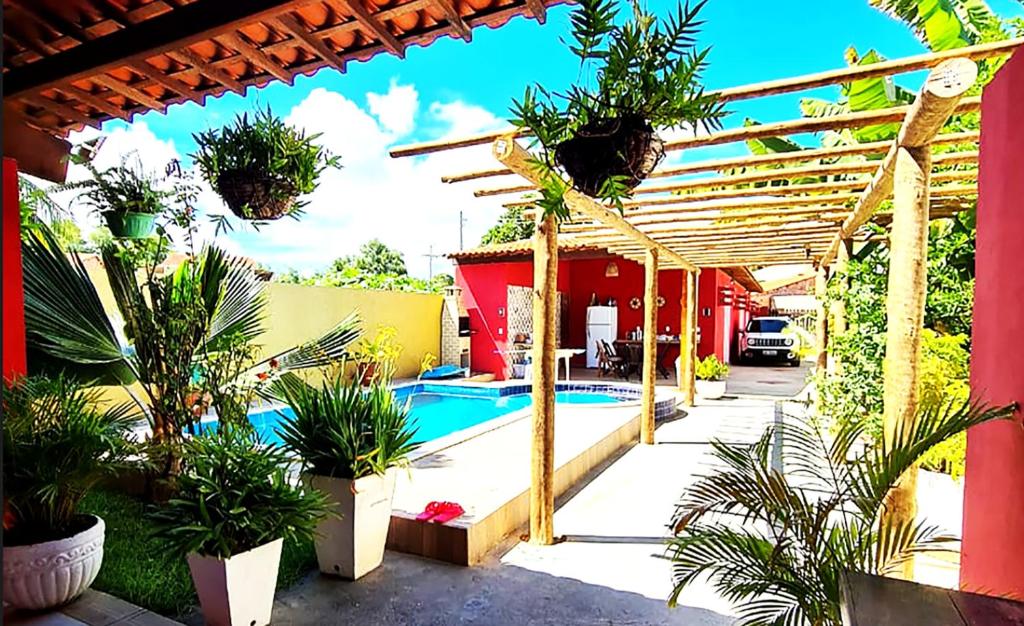 un patio con piscina y pérgola de madera en Casa com Wi-Fi e lazer em Porto de Pedras - AL, en Tatuamunha