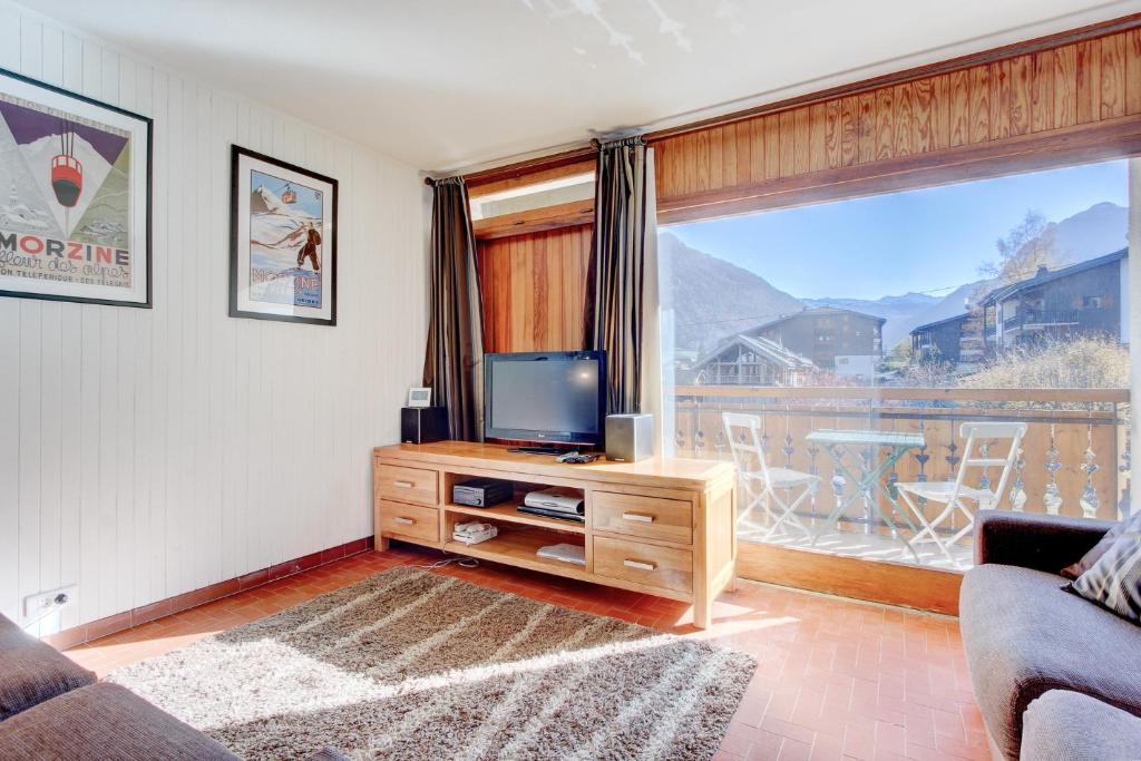 een woonkamer met een tv en een groot raam bij Nant Crue - Snow and Trek in Morzine